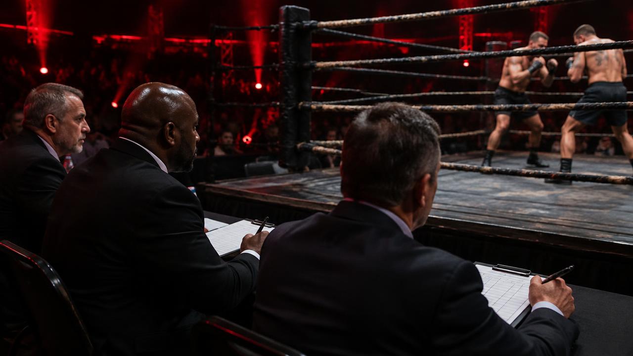 Three judges seated ringside scoring a bare-knuckle boxing round on the ten-point must system